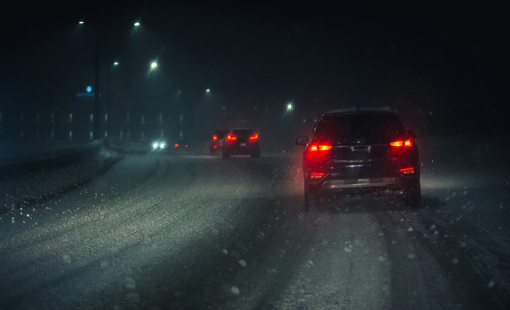 cars driving in a snow storm at night