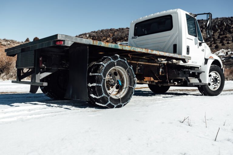 Flatbed work truck with chains and The Kranken installed in the snow