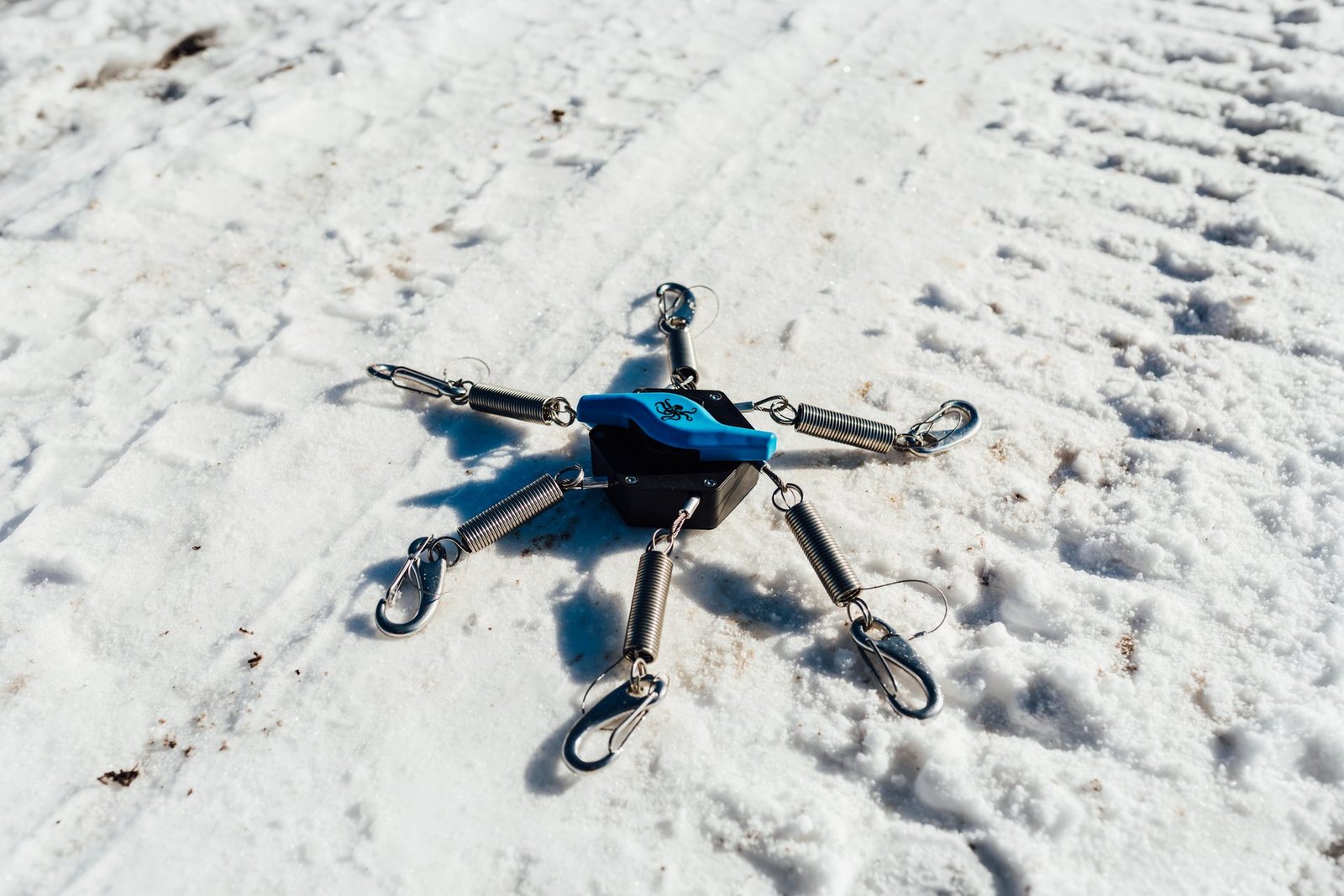 The Kranken XL product flat-lay on snow showing all six springs and clips