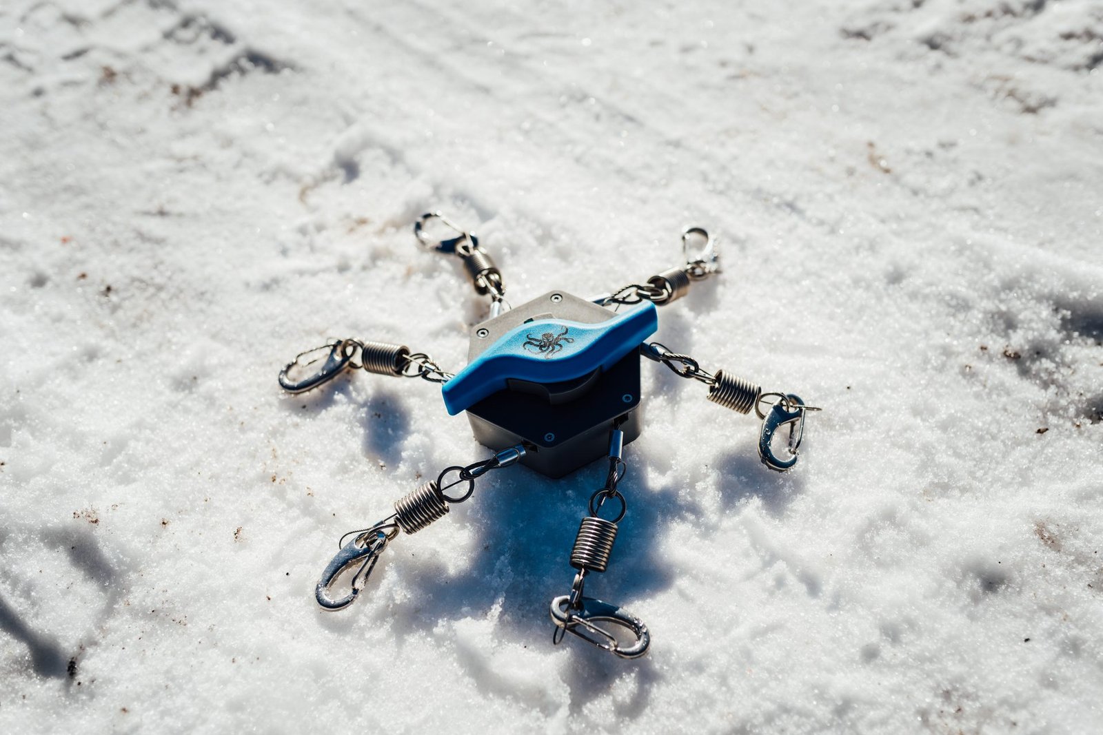 The Kranken tensioner flat-lay on snow showing all springs and clips